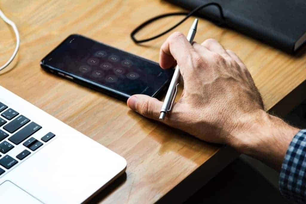Man Holding iPhone on Desk